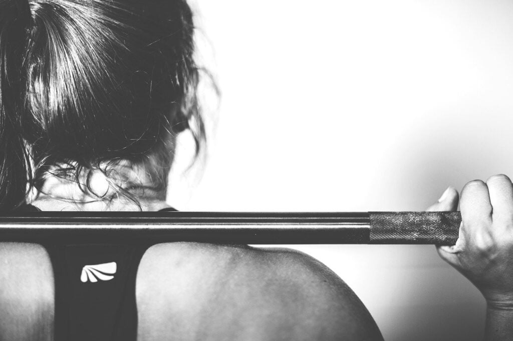 Female athlete with a barbell on her back in black and white