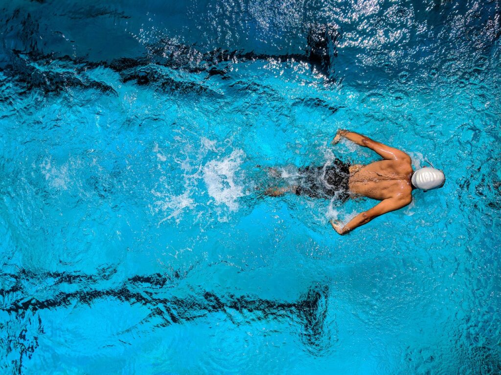 An overhead shot of a male swimmer in a pool swimming the butterfly stroke